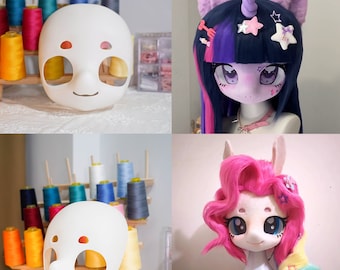 May include: A white blank mask with cutouts for eyes and eyebrows, alongside two finished character headpieces. One headpiece features dark blue hair with purple ears and a horn, the other has bright pink wavy hair with a rainbow braid.