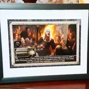 May include: A framed print of a historical painting depicting a scene from the Salem Witch Trials. The print includes a small vial of soil from Proctors Ledge, the site of the executions. The text reads: "The Salem Witch Trials occurred in Salem Massachusetts between 1692 & 1693. Proctors Ledge was the site of execution where 19 people were hung. This soil sample was collected at Proctors Ledge."