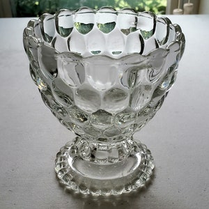 May include: A clear glass bowl with a textured, bubbled surface and a pedestal base. The bowl is perfect for serving desserts or snacks.
