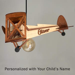 Personalized natural wood airplane lamp with child’s name – handmade biplane nursery light.