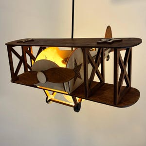 Wooden biplane airplane ceiling lamp with warm glow – cozy nursery night light.
