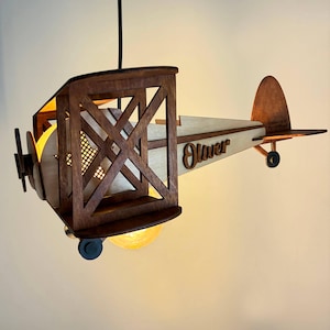 Handmade wooden airplane lamp with warm light – vintage biplane nursery night light.