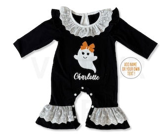 May include: Black baby romper with long sleeves, a white lace collar, and ruffled cuffs. A white ghost with an orange bow is printed on the front, with the name "Charlotte" below. The text "ADD NAME OR YOUR OWN TEXT!" is in a circle.
