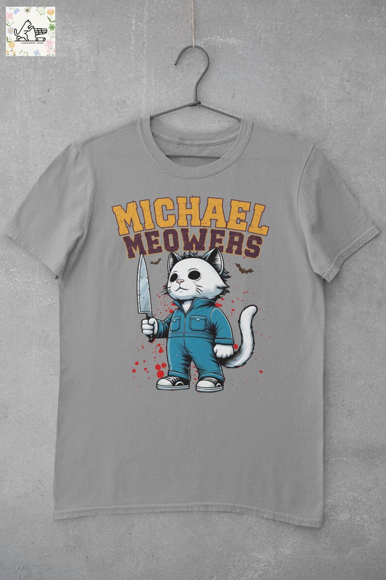 May include: A gray t-shirt with a graphic of a white cat holding a knife. The cat is wearing blue overalls and has a menacing expression. The text "MICHAEL MEOWERS" is printed above the cat.