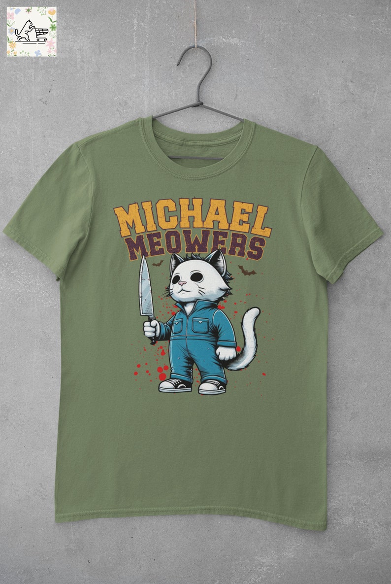 May include: A green t-shirt with a white cat holding a knife. The cat is wearing blue overalls and has a white mask. The text "MICHAEL MEOWERS" is printed in yellow above the cat.