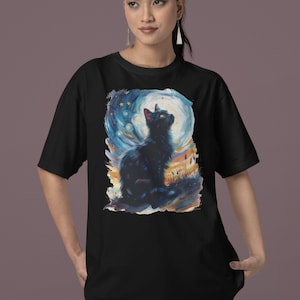 Könnte beinhalten: Schwarzes T-Shirt mit einer farbenfrohen Illustration einer schwarzen Katze, die zu einem Halbmond mit Sternen im Hintergrund aufblickt.