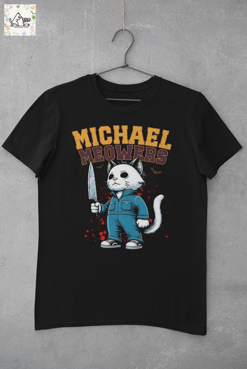 May include: Black t-shirt with a white cat wearing blue overalls and holding a knife. The text "MICHAEL MEOWERS" is above the cat.