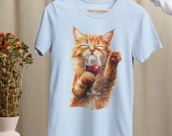 May include: A light blue t-shirt with a graphic of an orange cat holding a glass of red wine. The cat is looking at the wine glass and has a happy expression on its face.