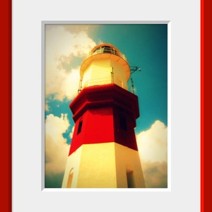 May include: A red and white lighthouse with a white roof against a blue sky with white clouds.