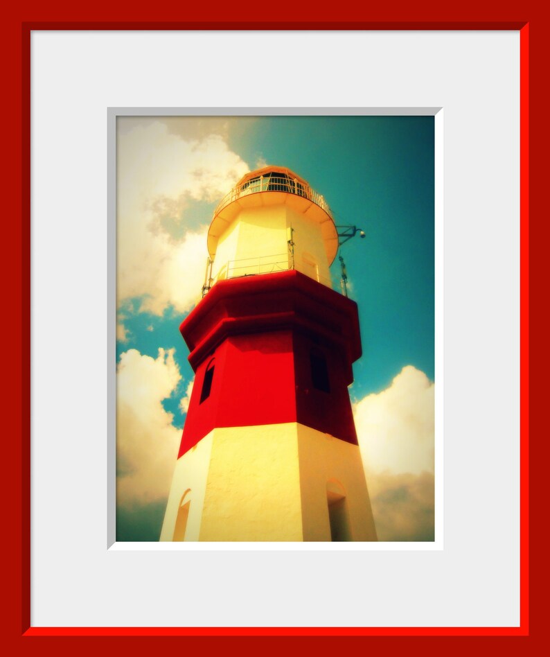 May include: A red and white lighthouse with a white roof against a blue sky with white clouds.