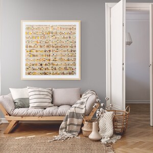 May include: A light gray living room with a wooden futon, a white stool, and a framed print of a wall of small jars filled with colorful spices. The futon has a white and gray striped throw blanket and two pillows. A wicker basket with a white knitted throw is on the floor next to the futon.