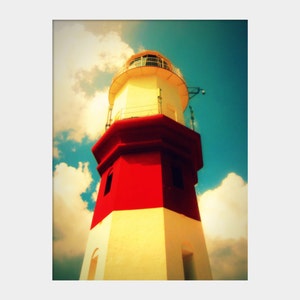 May include: A red and white lighthouse with a white roof and a small window. The lighthouse is against a blue sky with white clouds.