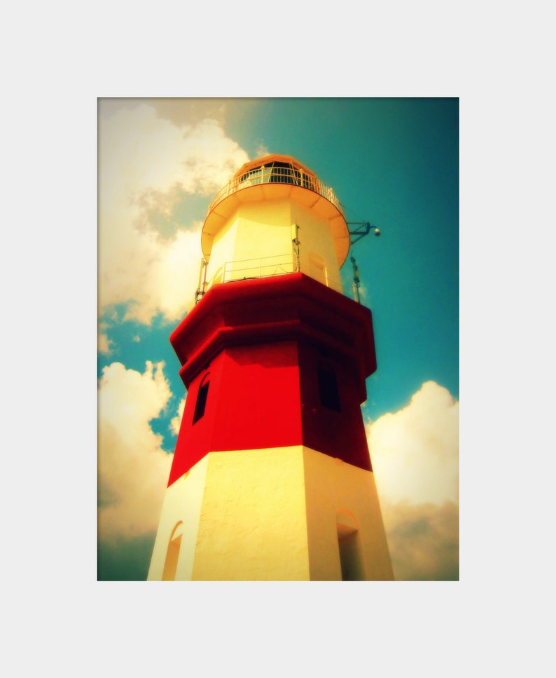 May include: A red and white lighthouse with a white roof and a small window. The lighthouse is against a blue sky with white clouds.