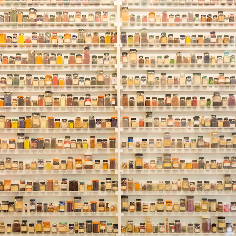 May include: A wall of shelves filled with small glass jars containing various colored powders. The jars are arranged in rows and columns, creating a colorful and organized display.