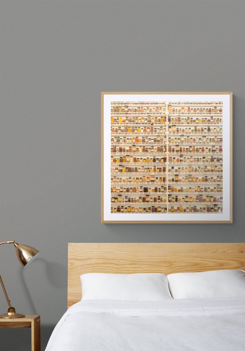 May include: A framed photograph of a wall filled with small glass jars containing various spices and herbs. The jars are arranged in rows and columns, creating a visually appealing pattern.