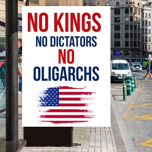 May include: A white poster with the text "NO KINGS, NO DICTATORS, NO OLIGARCHS" in red and blue. Below the text is a stylized American flag. The poster is displayed outdoors in an urban setting.