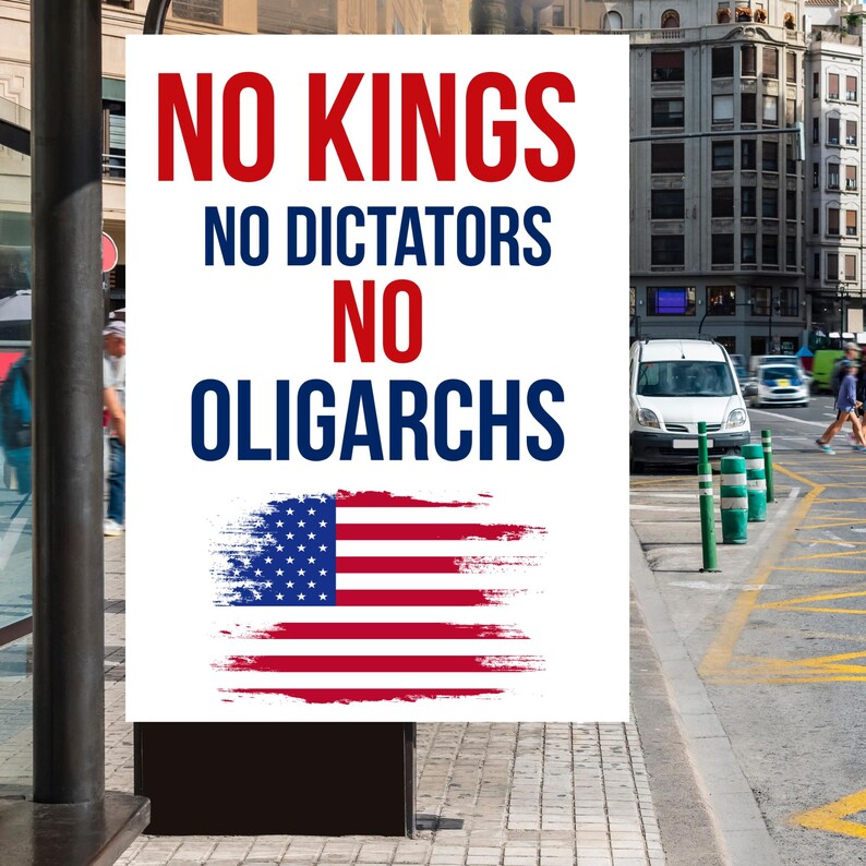 May include: A white poster with the text "NO KINGS, NO DICTATORS, NO OLIGARCHS" in red and blue. Below the text is a stylized American flag. The poster is displayed outdoors in an urban setting.