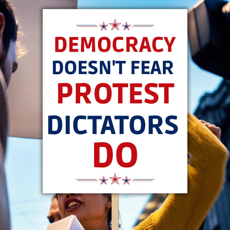 Puede incluir: Un cartel blanco con el texto "DEMOCRACY DOESN'T FEAR PROTEST DICTATORS DO" en rojo y azul. El cartel lo sostiene una persona entre la multitud, con un su&eacute;ter amarillo visible. El cartel tiene estrellas decorativas.