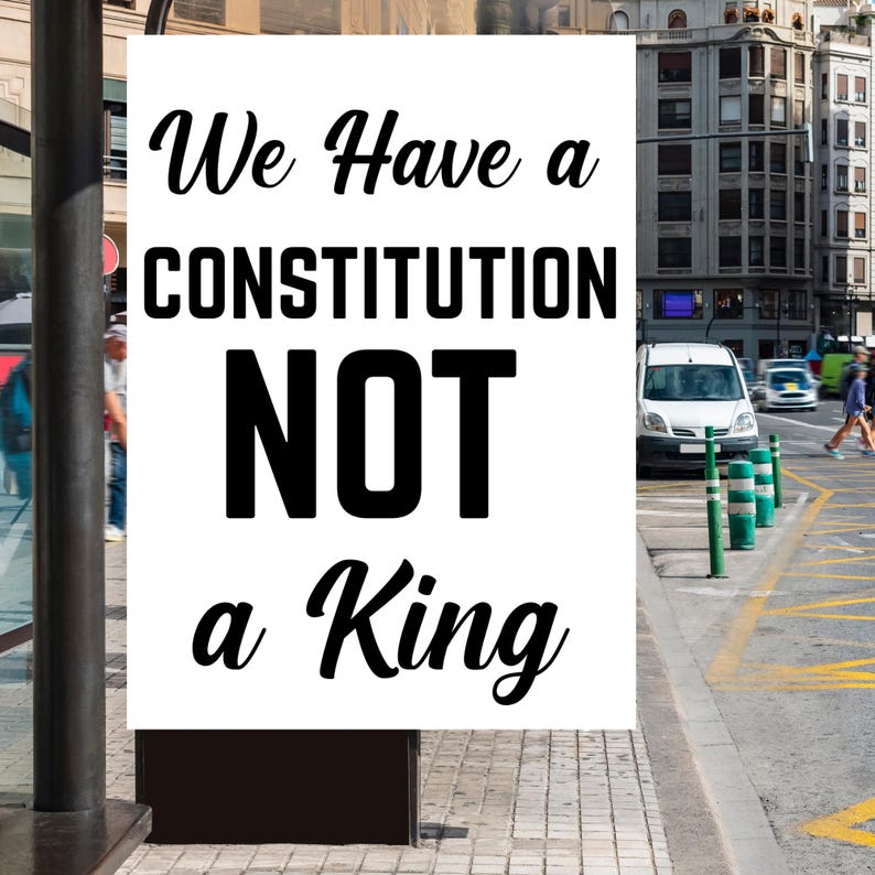 Puede incluir: Un letrero blanco con texto negro que dice "We Have a CONSTITUTION NOT a King." El letrero se muestra al aire libre, con una calle de la ciudad y edificios al fondo.