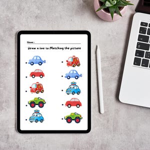 May include: A worksheet with the text "Draw a line to Matching the picture" and a series of images of different colored cars. The cars include a red fire truck, a blue police car, a green monster truck, and a red car. The worksheet is designed for children to practice matching.