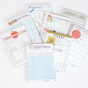 May include: A collection of various notepads with different designs and text. The notepads include a student report card, dental exam, daycare log, pet clinic exam, medical appointment, restaurant guest check, library card, and a ticket.