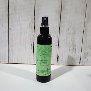 May include: A black spray bottle with a green and white label. The label reads "Bennett Family Farms Flea & Tick Spray" with a paw print logo. The bottle contains 118 ml of product and is designed for dogs and cats.
