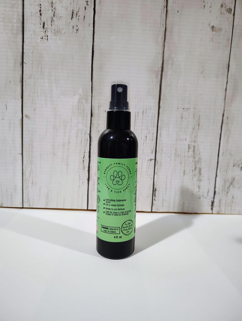 May include: A black spray bottle with a green and white label. The label reads "Bennett Family Farms Flea & Tick Spray" with a paw print logo. The bottle contains 118 ml of product and is designed for dogs and cats.