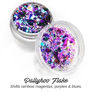 May include: Two small jars filled with iridescent glitter flakes. The glitter shifts colors from magenta, purple, and blue.