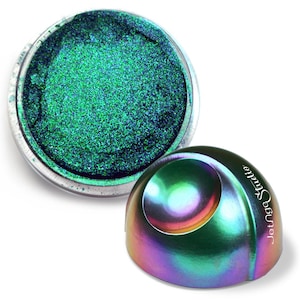 Puede incluir: Un tarro de sombra de ojos verde brillante con un acabado metálico. El recipiente abierto revela el producto, mientras que la tapa iridiscente en forma de cúpula está al lado. La tapa tiene el texto "Jettga Studio" impreso.