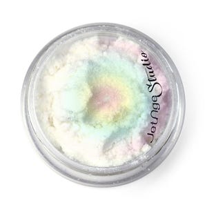 May include: A clear, round container filled with iridescent, pastel-colored powder. The powder has a soft, blended appearance with hues of pink, yellow, and blue. The text "JetAge Studio" is printed on the side of the container.