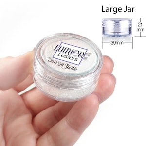 May include: A clear plastic jar filled with white iridescent glitter. The jar is labeled "Lumiere Lusters by JetAge Studio". The jar is 39 mm in diameter and 21 mm in height.