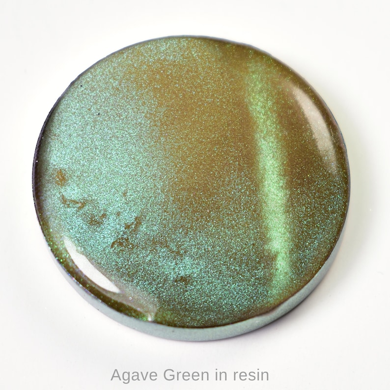 May include: A circular resin piece with a colour gradient of agave green and gold. The surface has a speckled, glittery appearance. The text "Agave Green in resin" is at the bottom of the image.