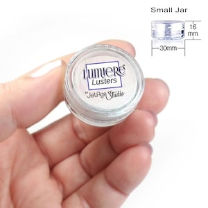 May include: A small jar of Lumiere Lustre by Jet Age Studio. The jar is 30 mm in diameter and 16 mm tall. The jar is filled with a white iridescent powder.