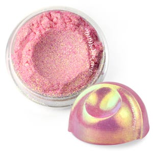 May include: A small, round, clear plastic container filled with loose, shimmering pink pigment powder. The lid is dome-shaped with an iridescent, color-shifting finish that transitions between pink and gold. The text Jounge Studio is visible.