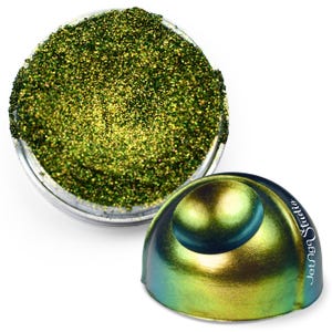 May include: A clear container filled with green glitter next to a metallic, iridescent dome-shaped object. The dome has a spherical top and the text "Jetunge Studio" on its side. The glitter appears to be finely ground.