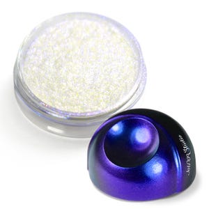 May include: A clear jar filled with iridescent glitter next to a purple and blue decorative object. The object has a spherical shape with the words "Jounge Studio" printed on the side. The glitter appears white and reflects light.
