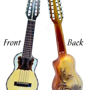 Könnte beinhalten: Vorder- und Rückansicht eines Charango, eines kleinen Anden-Zupfinstruments. Die Vorderseite ist hellgelb mit einem dunkelbraunen Schallloch und Griffbrett. Die Rückseite ist braun mit einem geschnitzten Lama-Design. Die Wörter "Front" und "Back" sind sichtbar.