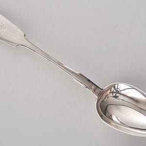 May include: A silver spoon with an ornate handle and a rounded bowl. The handle is engraved with a monogram.