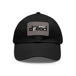 May include: Black cotton baseball cap with a grey patch that says "existential dread" in white letters with a skull icon.