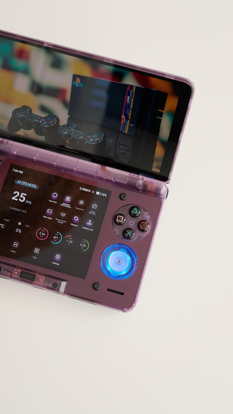 May include: A purple handheld gaming console with a screen displaying a retro game interface. The console features a D-pad, action buttons, and a glowing blue power button. The screen shows 25 FPS and other performance metrics.