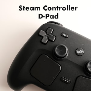 Puede incluir: Un mando de juego Steam Controller negro con una cruceta D-Pad prominente, dos trackpads circulares, un botón central con el logotipo de Steam y varios botones de función. El texto Steam Controller D-Pad aparece sobre el mando.