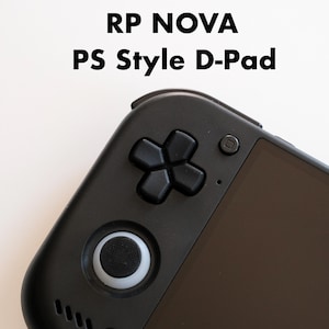 以下が含まれることがあります： RP NOVA PS Style D-Padというテキストが記載された黒い携帯ゲーム機。黒い十字キー、白いリングが付いた円形のアナログスティック、小さな丸いボタン、暗い画面が特徴です。
