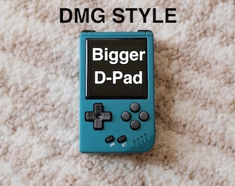 May include: Teal handheld gaming device with a black screen displaying "Bigger D-Pad." The device has a D-pad, four black buttons, and the text "SE" and "ST." The text "DMG STYLE" is above the device. The background is a textured, off-white surface.