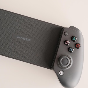 May include: A dark gray GameSir mobile gaming controller. The controller has a textured grip and features a directional pad, buttons, and analog sticks. The GameSir logo is visible on the device. The controller is designed for mobile gaming.