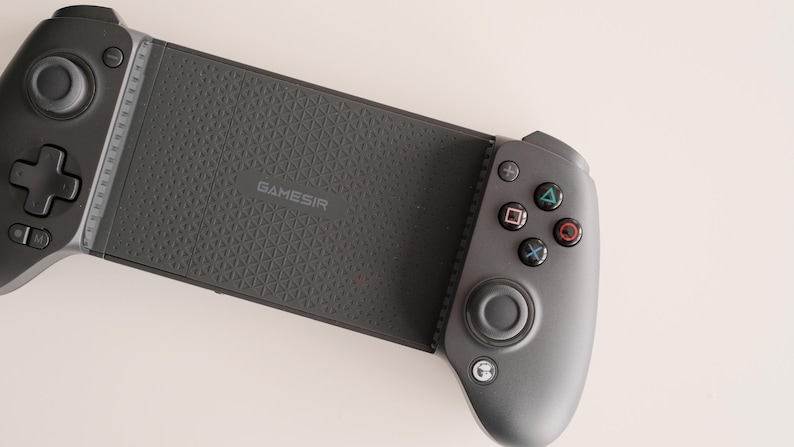 May include: A dark gray GameSir mobile gaming controller. The controller has a textured grip and features a directional pad, buttons, and analog sticks. The GameSir logo is visible on the device. The controller is designed for mobile gaming.