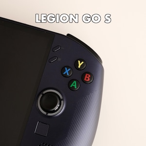 May include: A dark blue handheld gaming console with the text LEGION GO S visible above the screen. The device features a black joystick, a square button, and four colored action buttons labeled X in blue, Y in yellow, B in red, and A in green.