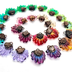 Puede incluir: Surtido de abalorios de flores de vidrio de colores con detalles en cobre. Cada abalorio presenta un diseño de flor único con un centro texturizado y un bucle para sujetarlo a joyas u otras manualidades.