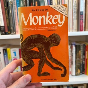 May include: A vintage paperback book titled "Monkey" by Wu Ch'êng-ên. The cover is orange with a brown illustration of a monkey. Text includes "Now a major BBC television series" and a quote from The Spectator.