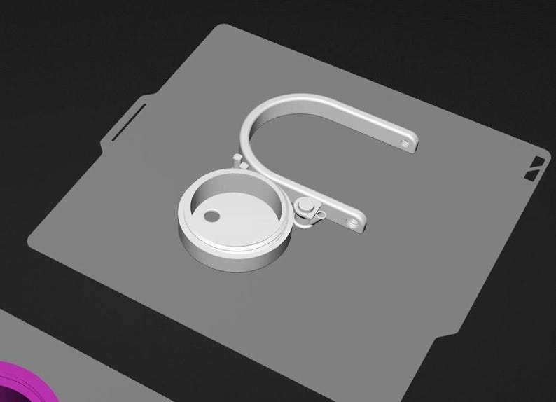 A 3D rendering of a metal object with a circular opening, placed on a gray surface.