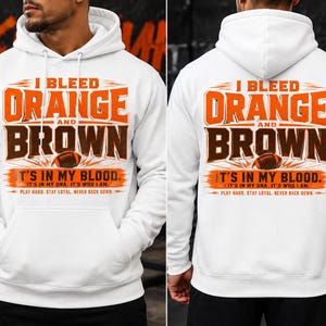 以下が含まれることがあります： I BLEED ORANGE AND BROWN IT'S IN MY BLOOD. IT'S IN MY DNA. IT'S WHO I AM. PLAY HARD. STAY LOYAL. NEVER BACK DOWN. というテキストと茶色のフットボールのイラストがプリントされた、白いフード付きスウェットシャツ。